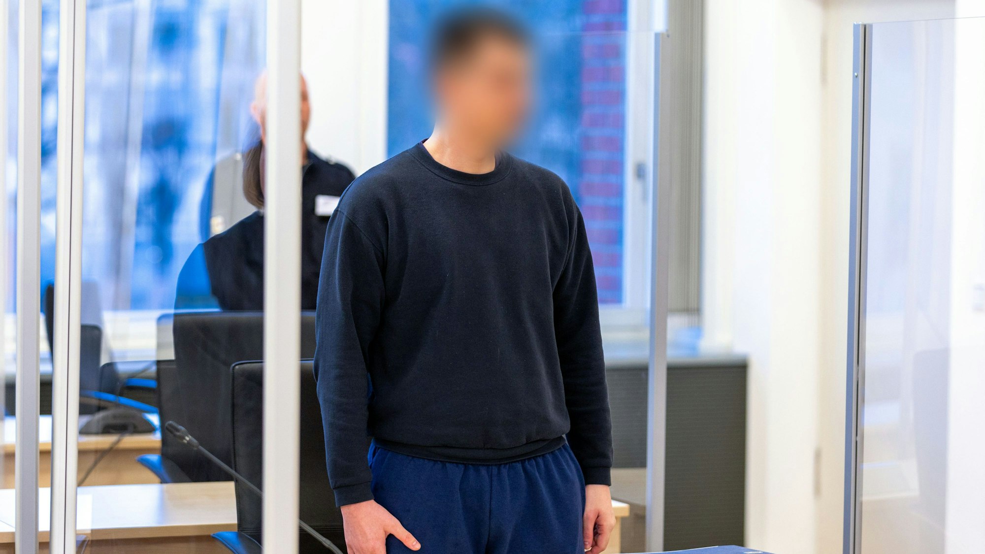 Der Angeklagte steht hinter der Anklagebank im Gerichtssaal vom Landgericht Rostock.