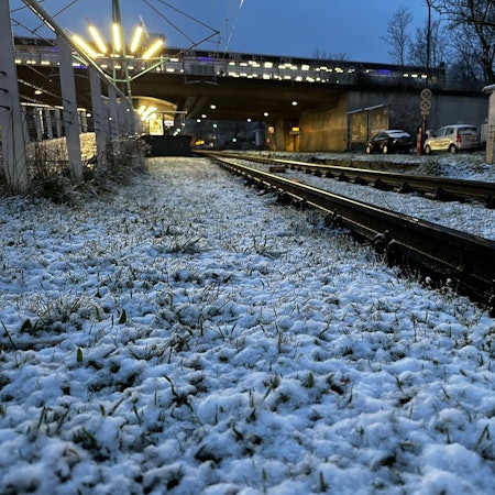 Ein Grünstreifen an der KVB-Haltestelle Amsterdamer Straße/Gürtel in Köln ist mit etwas Schnee bedeckt. In der Nacht zu Mittwoch hat es in Köln geschneit.