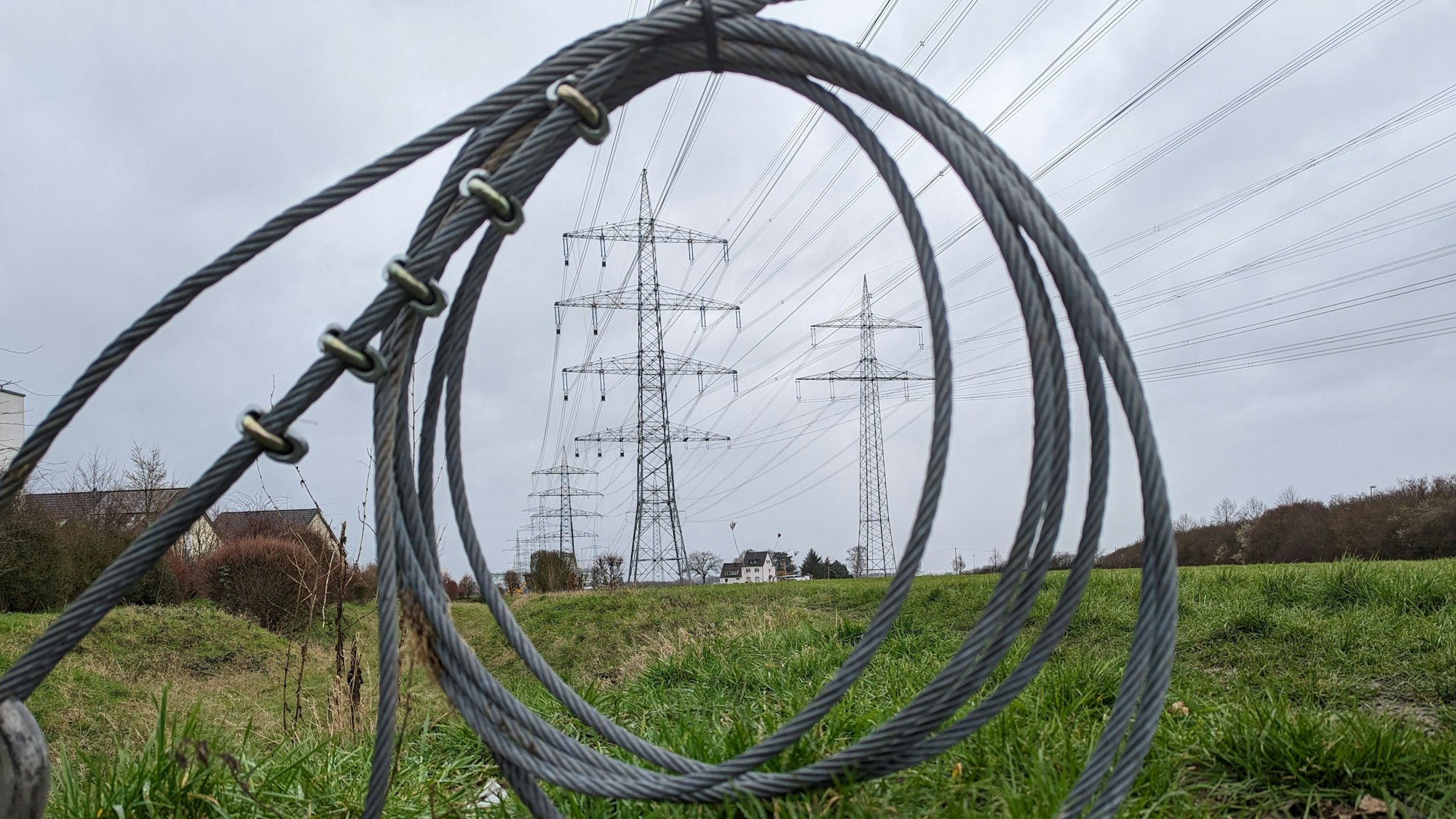 In Hürth beschweren sich Anwohner über peitschende Geräusche von den im Bau befindlichen Hochspannungsmasten. Das Foto zeigt Stahlkabel und im Hintergrund die Masten.