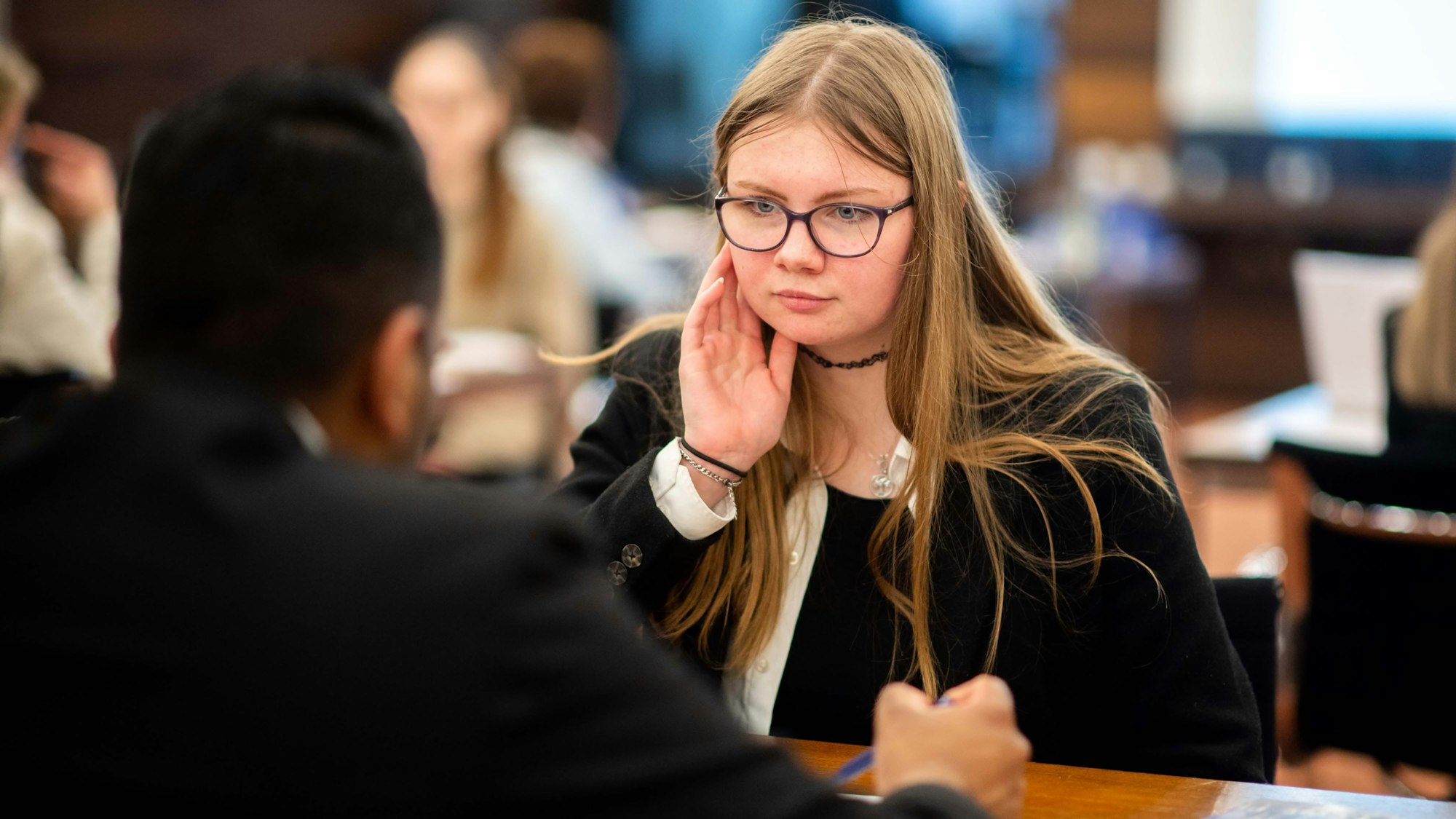 Patricia sitzt am Tisch und hört gespannt zu.