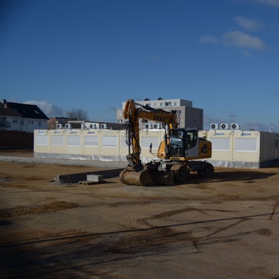 Ein Bagger steht vor mehreren Containern.