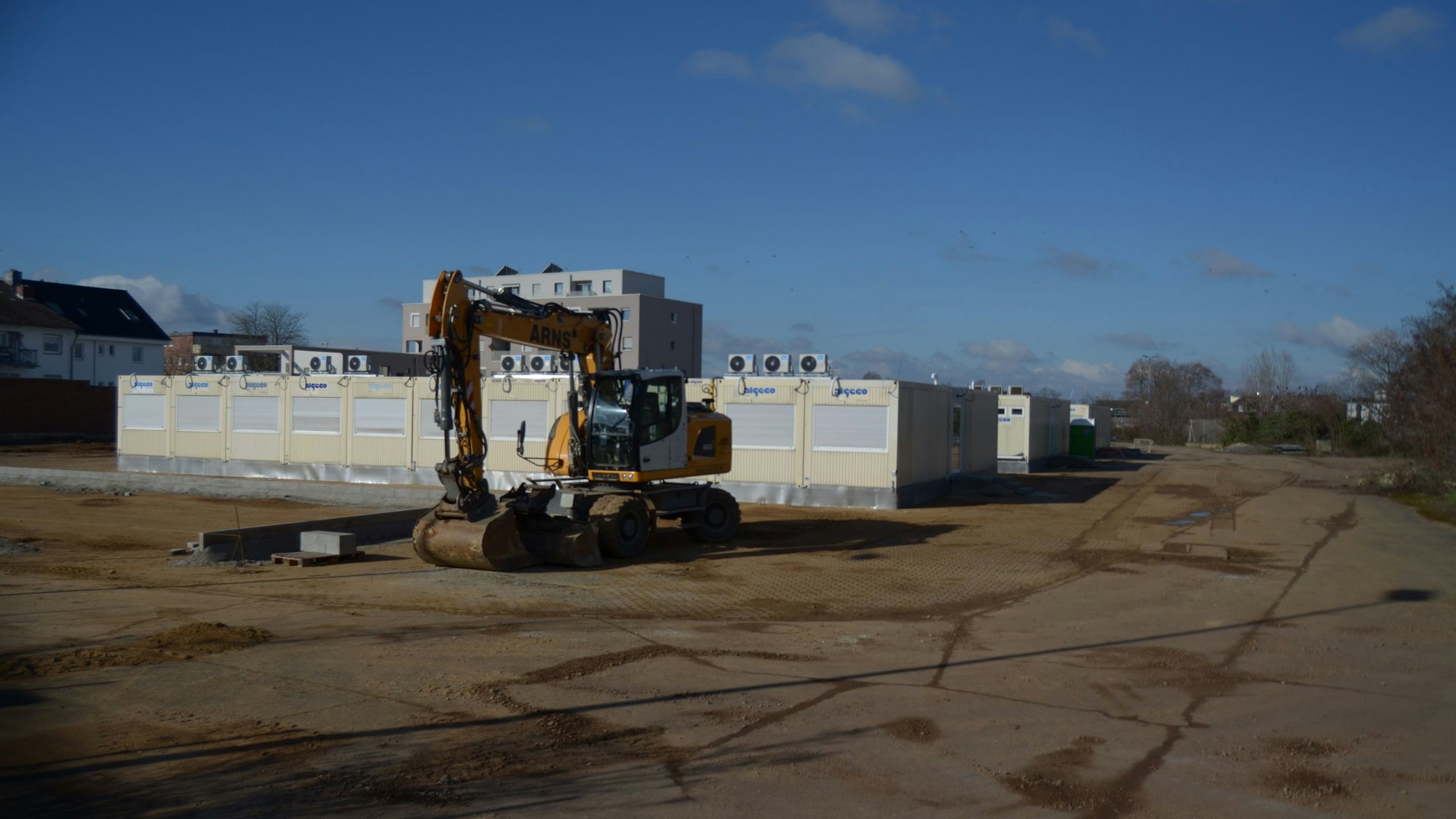 Ein Bagger steht vor mehreren Containern.