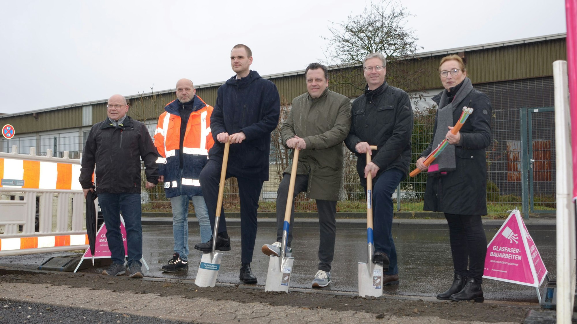 Mit Spaten und Glasfaser in der Hand blicken die Personen in die Kamera.