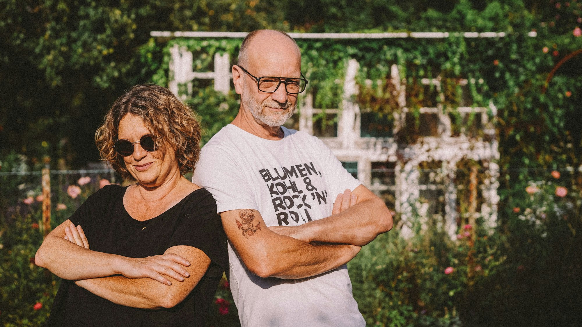 Anja und Andreas stehen Rücken an Rücken und gucken in die Kamera.