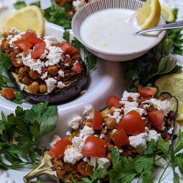 Man sieht die gefüllte Aubergine, daneben eine Schale mit dem Dip.