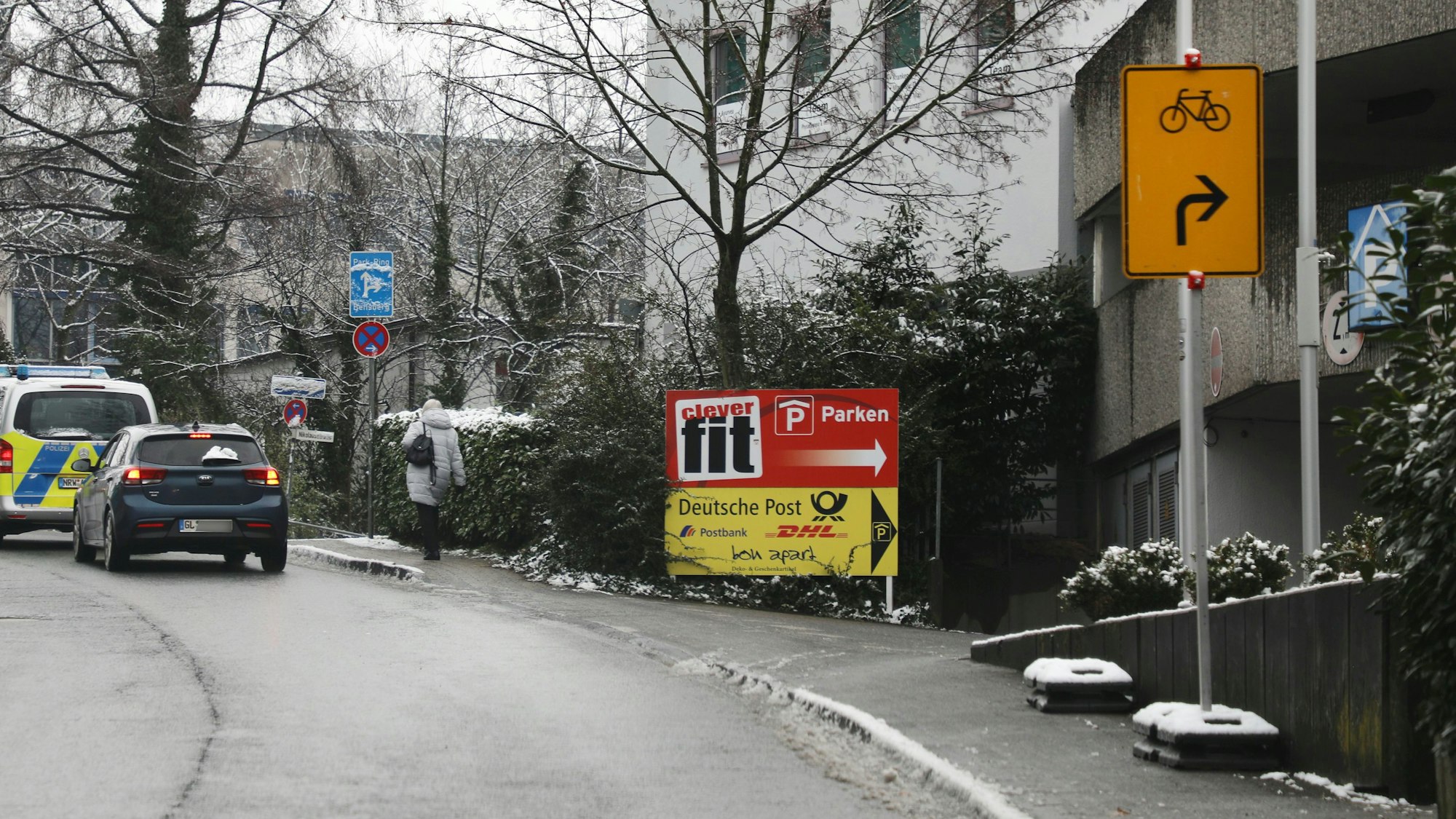 Ein Umleitungsschild für Fahrräder steht auf dem Gehweg neben einer Straße in einem Hartgummi-Fuß. Dahinter steht ein weiterer Hartgummi-Schilderfuß, allerdings ohne Schild.