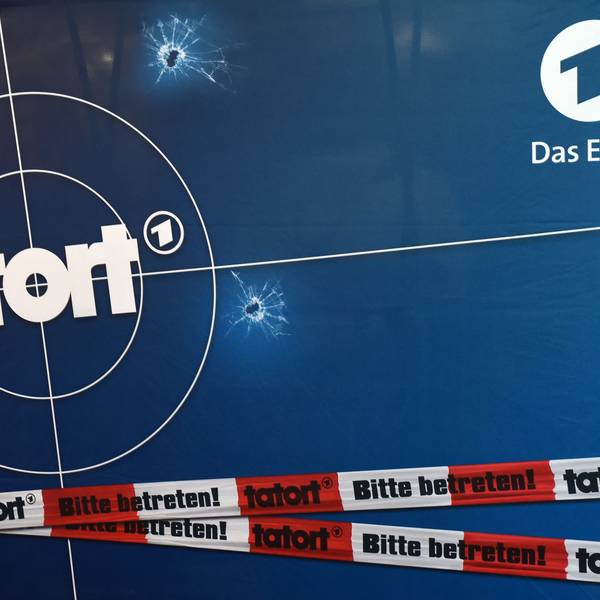 Auf einer Fotorückwand sind das Logo der ARD-Fernsehreihe „Tatort“, Einschusslöcher und Absperrband abgebildet.
