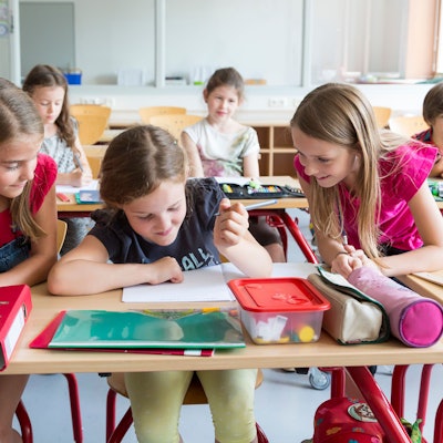 Drei Mädchen in der Grundschule machen zusammen Aufgaben in der Klasse.