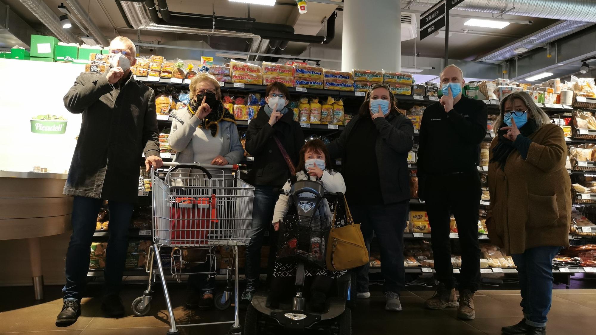 Beteiligte der „Stille Stunde“ haben sich zu einem Gruppenbild im Supermarkt zusammengestellt.