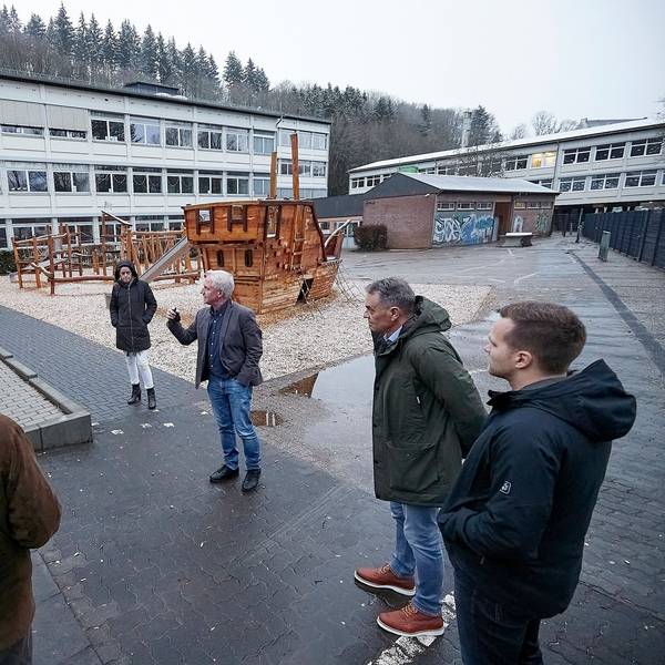 Schulleiter Wolfgang Schmitz und die Mitglieder des Ausschusses stehen auf dem Schulhof der Astrid-Lindgren-Förderschule.