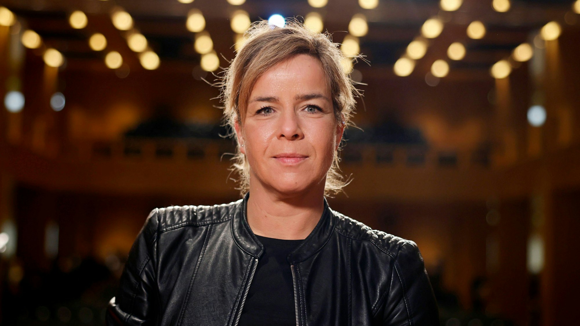 Mona Neubaur (Grüne), Ministerin für Wirtschaft, Industrie, Klimaschutz und Energie des Landes Nordrhein-Westfalen, ist bei einem Empfang zu sehen, hinter ihr sind viele Lichtpunkte an der Decke zu sehen.