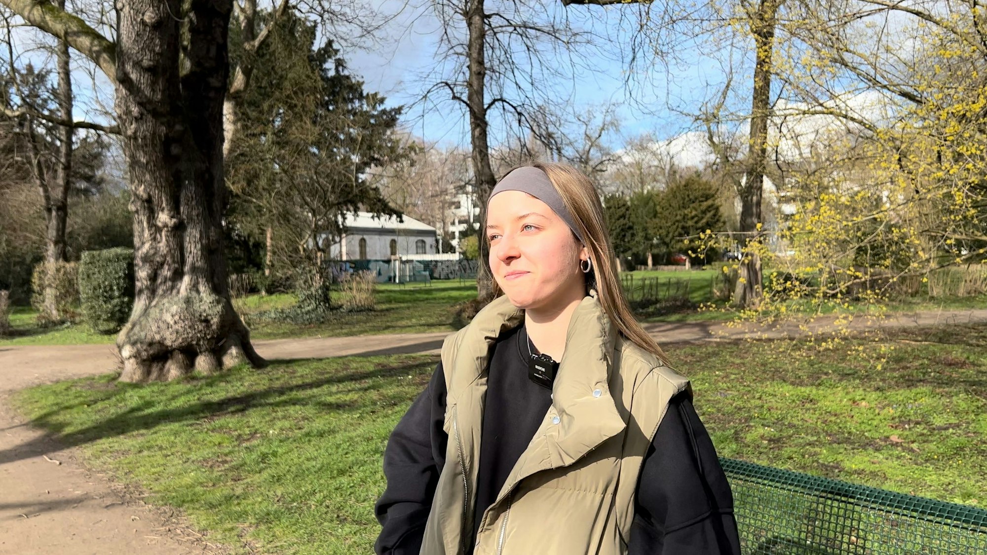 Ein blonde Frau mit Stirnband steht im Volksgarten.