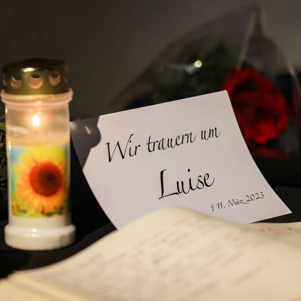 Ein Kondolenzbuch liegt neben Blumen und Kerzen in einer Kirche aus.