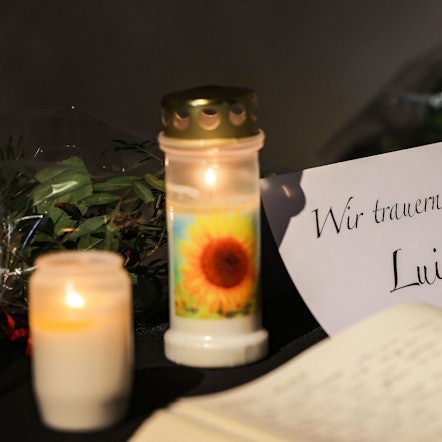 Ein Kondolenzbuch liegt neben Blumen und Kerzen in einer Kirche aus.
