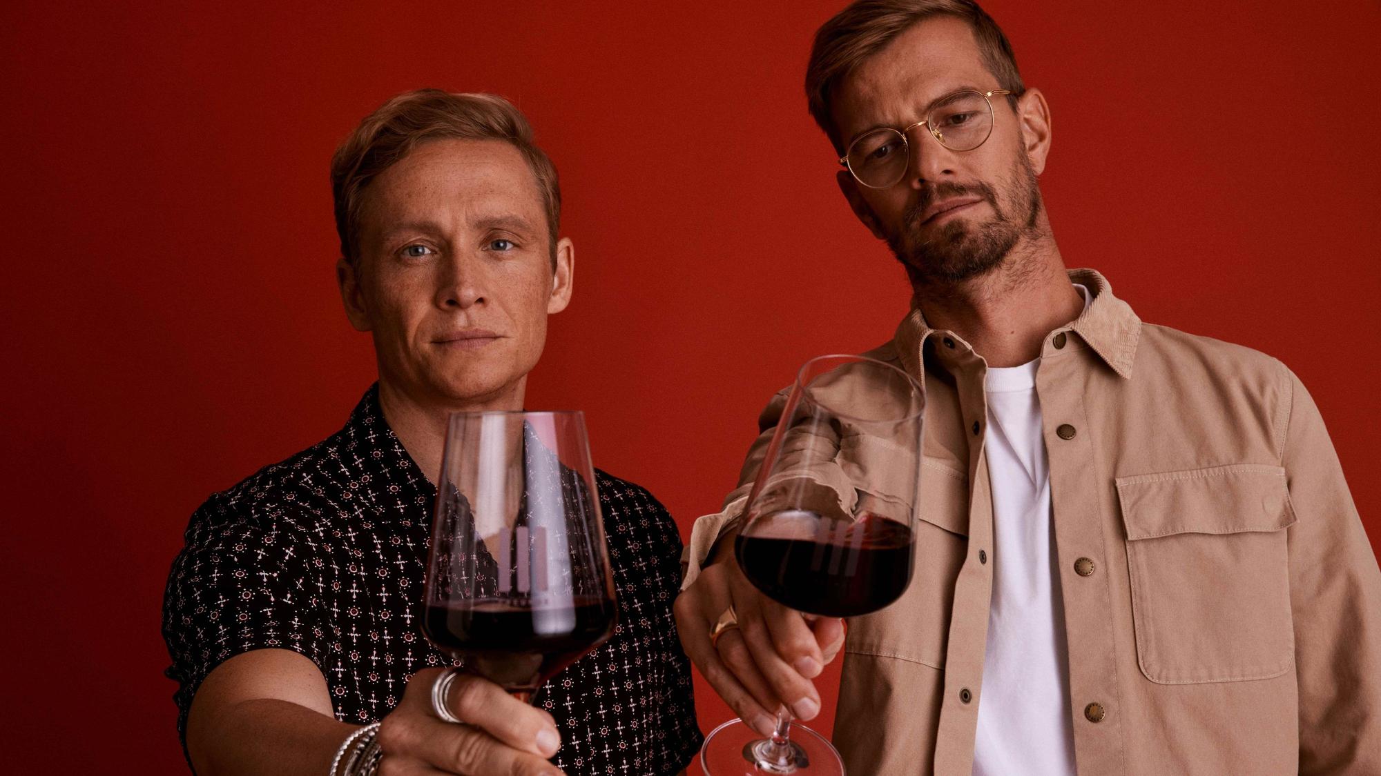 Schauspieler Matthias Schweighöfer und Moderator Joko Winterscheidt mit Weingläsern. In beiden ist Rotwein.