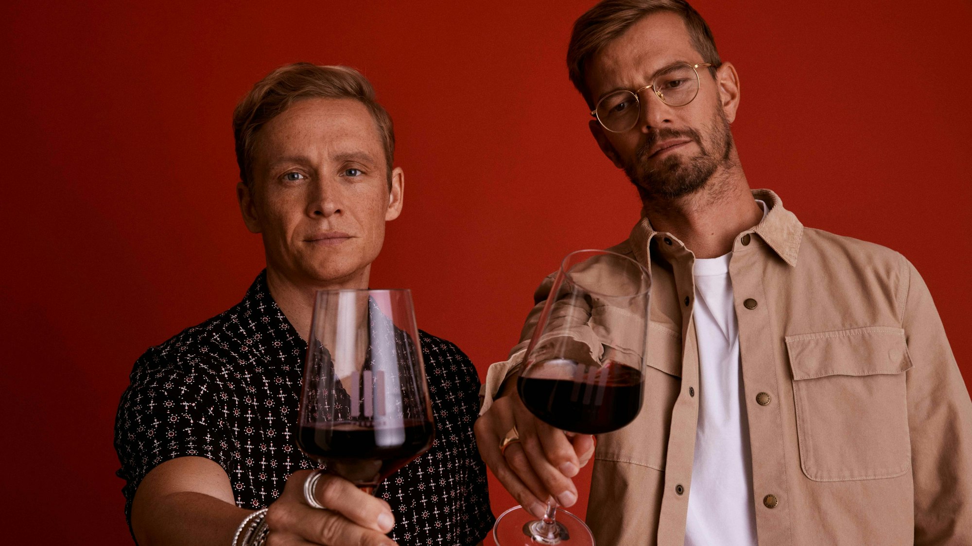 Schauspieler Matthias Schweighöfer und Moderator Joko Winterscheidt mit Weingläsern. In beiden ist Rotwein.