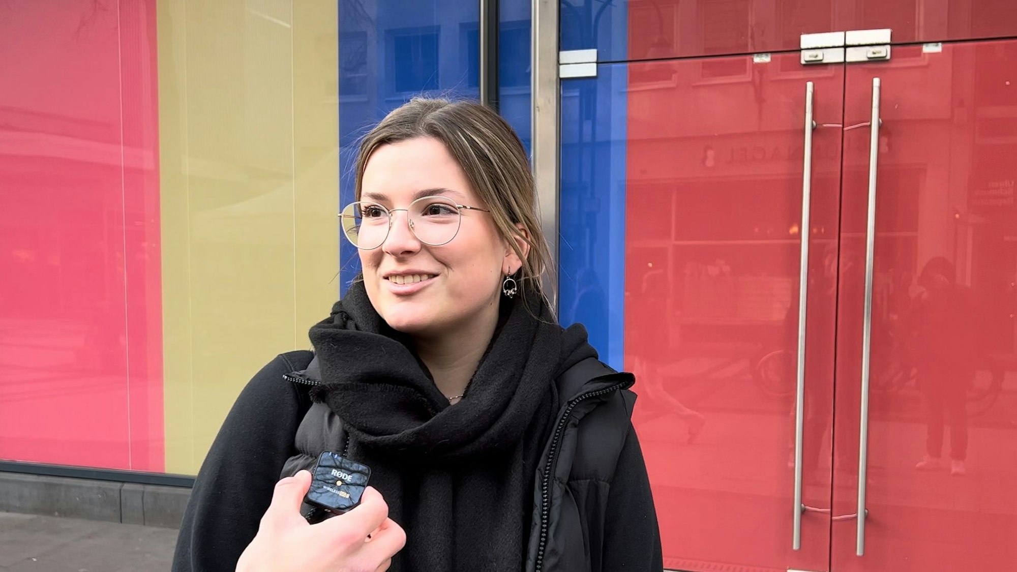 Eine Frau steht vor einer bunten Wand.