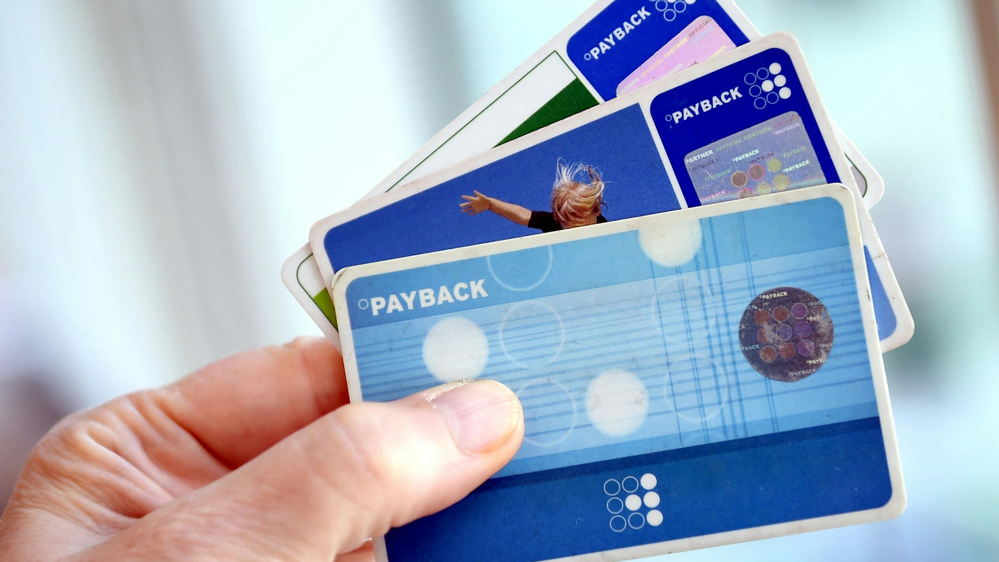 Eine Person hält Karten des Bonussystems Payback.