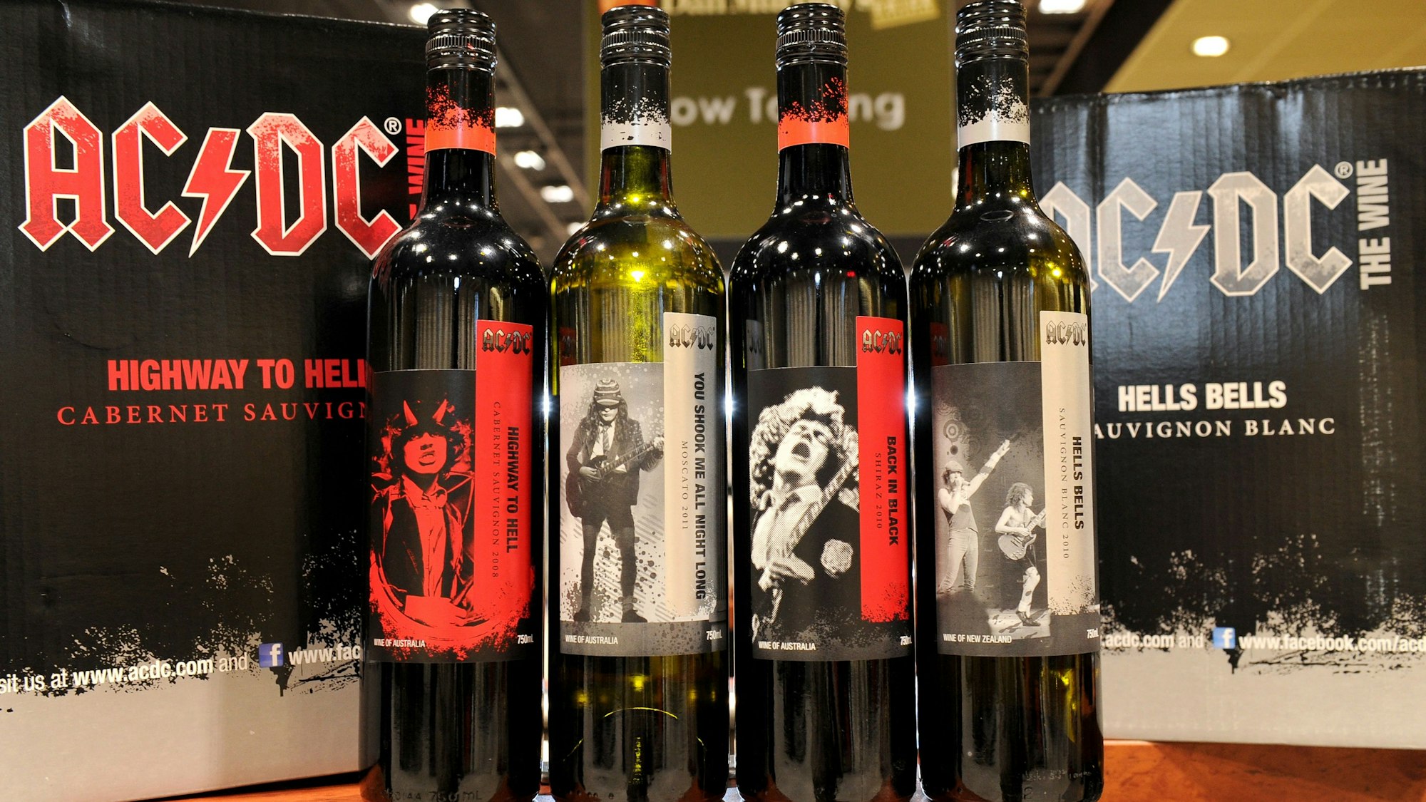 Die Weine der Metal-Band AC/DC. Vier Flaschen nebeneinander, dahinter die Weinkisten.