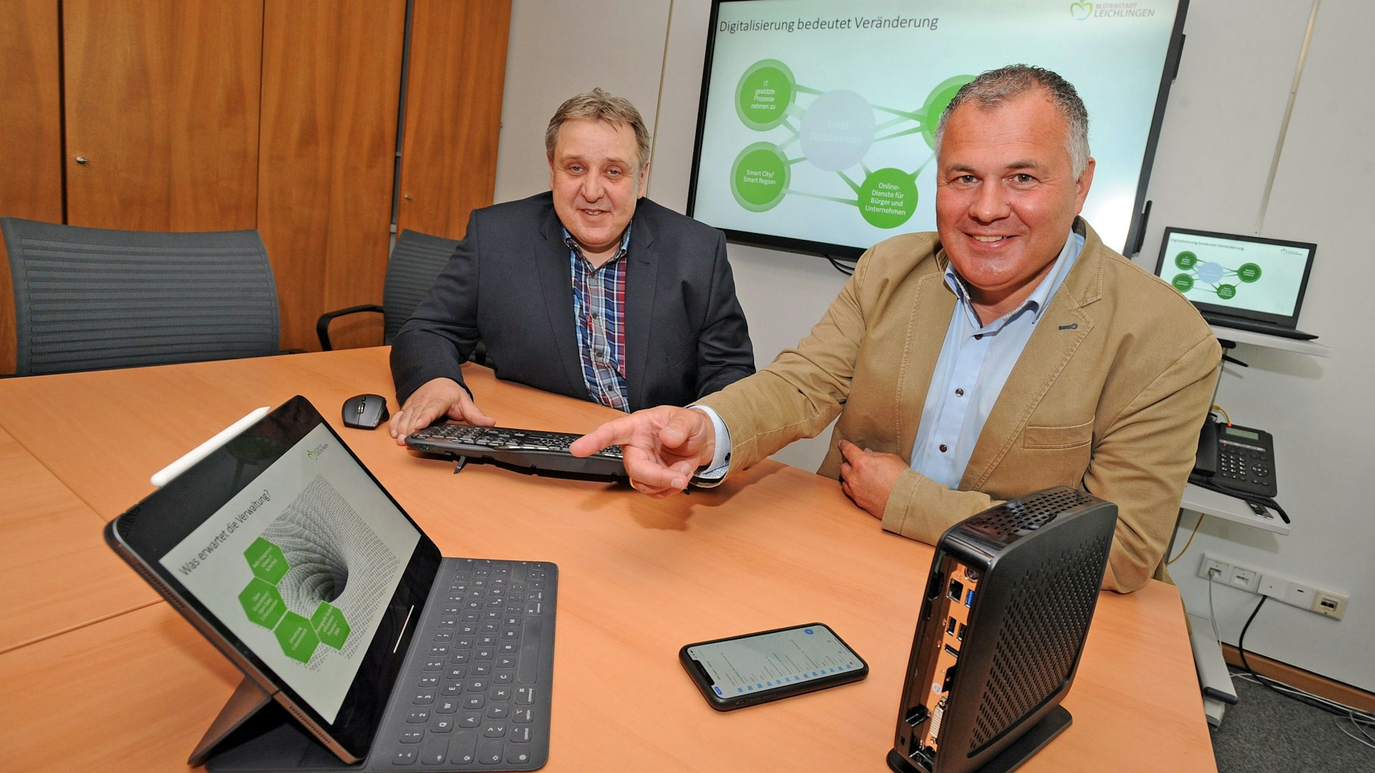 Jörg Brauckhoff und Frank Steffes sitzen mit Ipad und neuem Rechner am Schreibtisch.