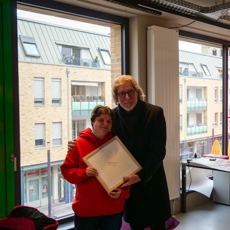 Das Foto zeigt Nicole Fellmann und Toni Schumacher. Sie schenkte der Torwart-Legende ein von ihr geschriebenes Gedicht in einem Bilderrahmen.