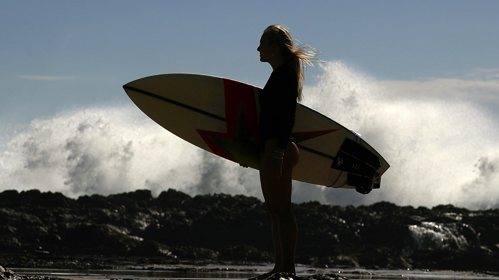 Eine Surferin steht an den Snapper Rocks an der Gold Coast.