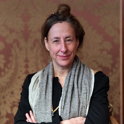 Judith Hermann steht vor einer Tapete mit rot-goldenen Ornamenten.