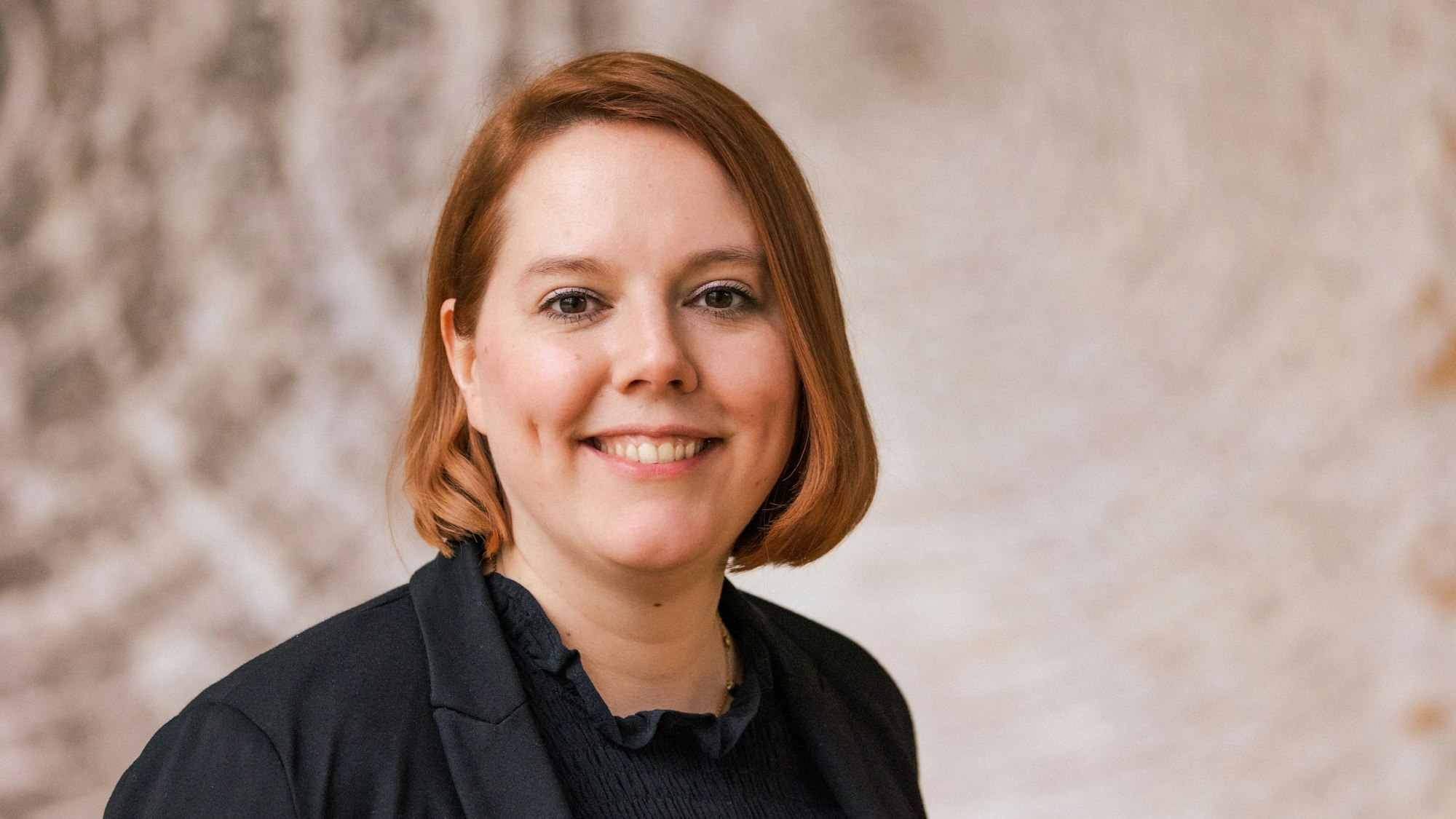 Müller-Rech blickt für ein Porträtfoto in die Kamera. Sie hat kinnlange rote Haare.