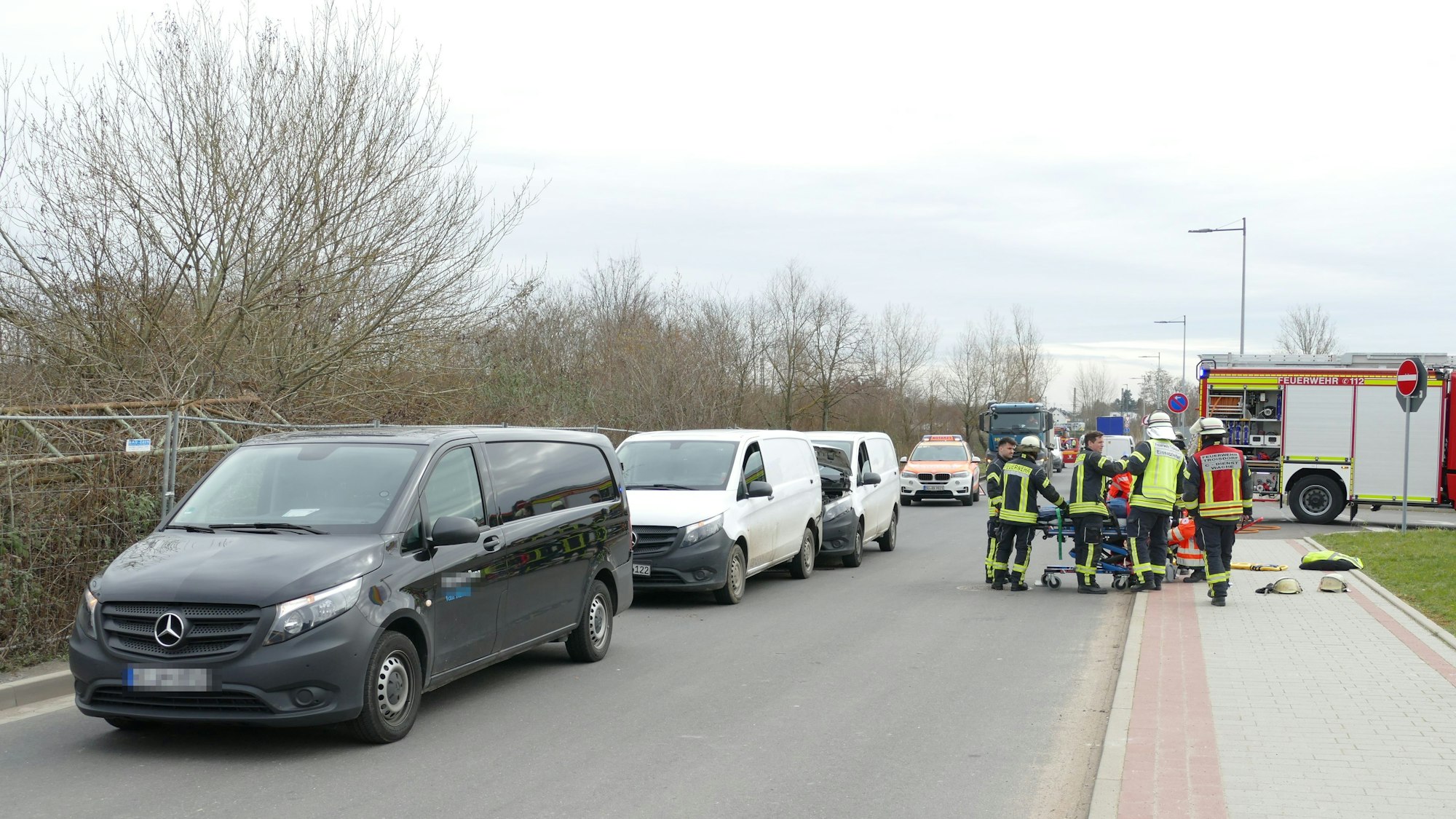 Man sieht die drei Transporter auf der Straße, dahinter und daneben Polizei und Notarzt.