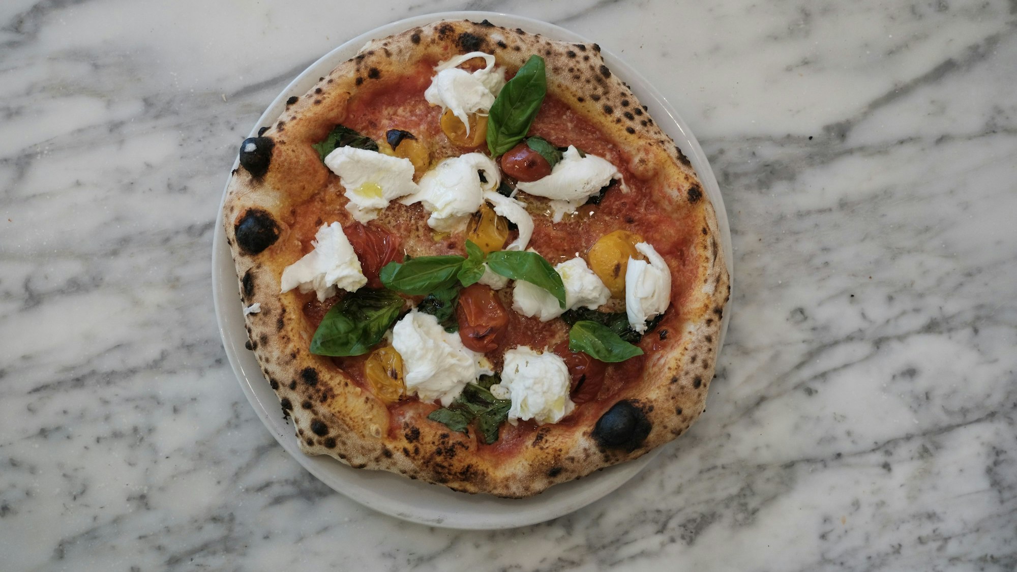 Pizza mit Mozzarella, Tomaten und Basilikum