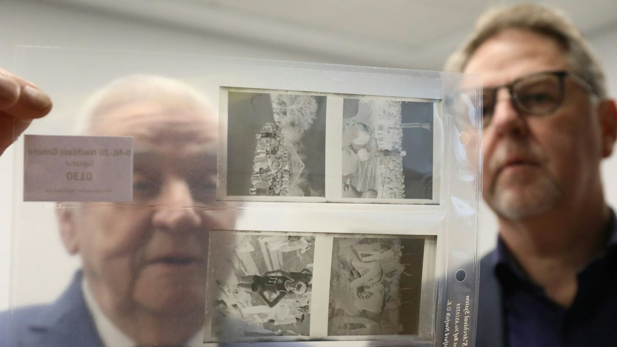 Zwei Personen sichten Negative in einer Klarsichthülle.