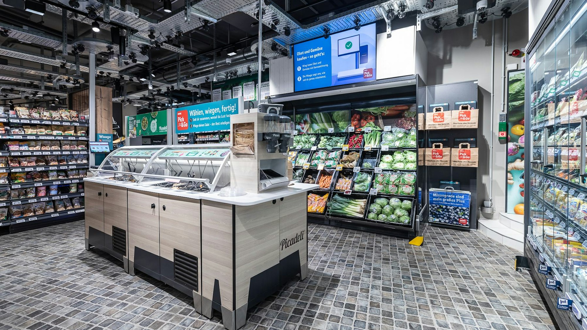 Eine Salatbar und eine Obst- und Gemüsetheke in einem Rewe-Supermarkt an der Luxemburger Straße in Köln.