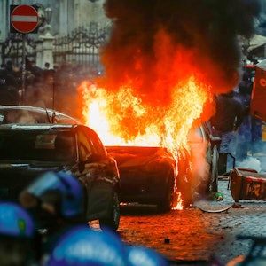 Vermummte Hooligans randalieren vor dem Spiel auf einer Straße in Neapel.