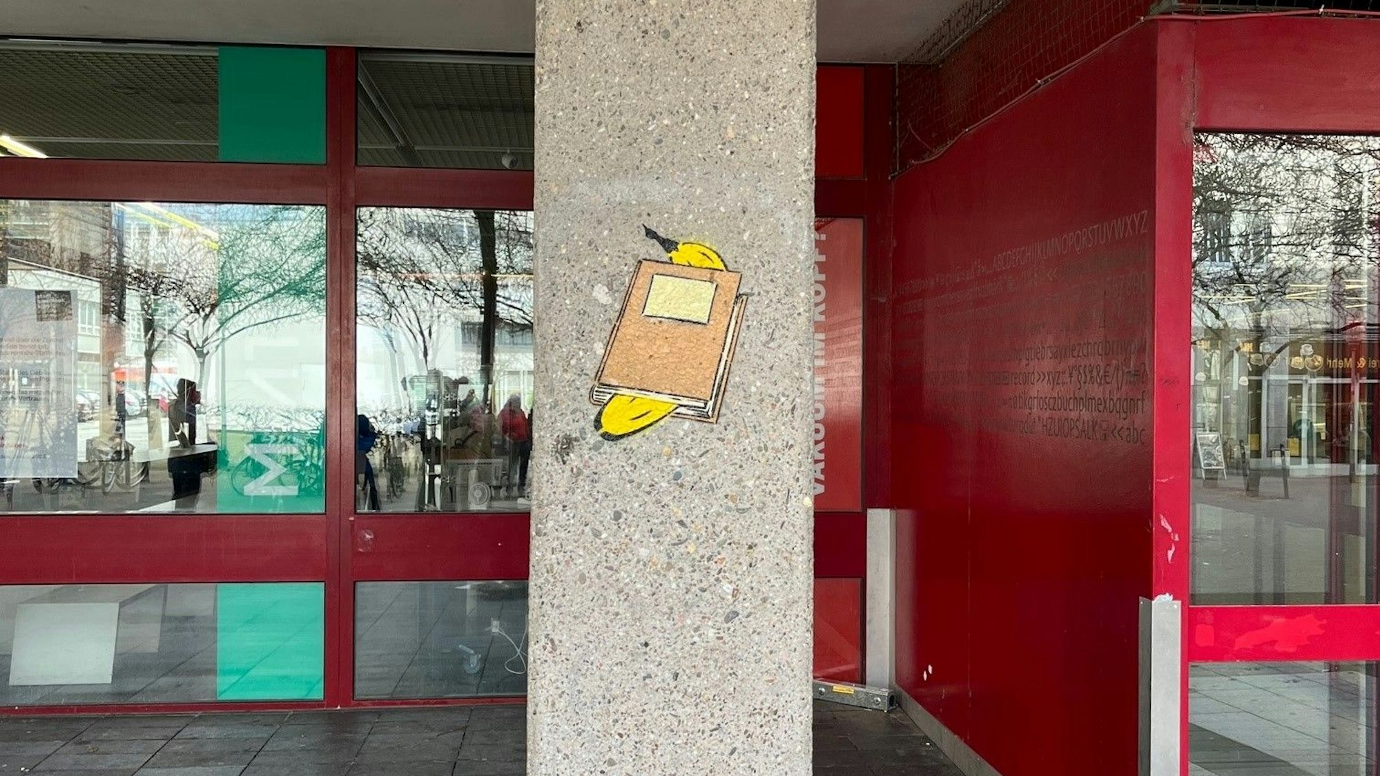 Das Bild zeigt eine gesprayte Banane in einem Buch auf einem Betonpfeiler.