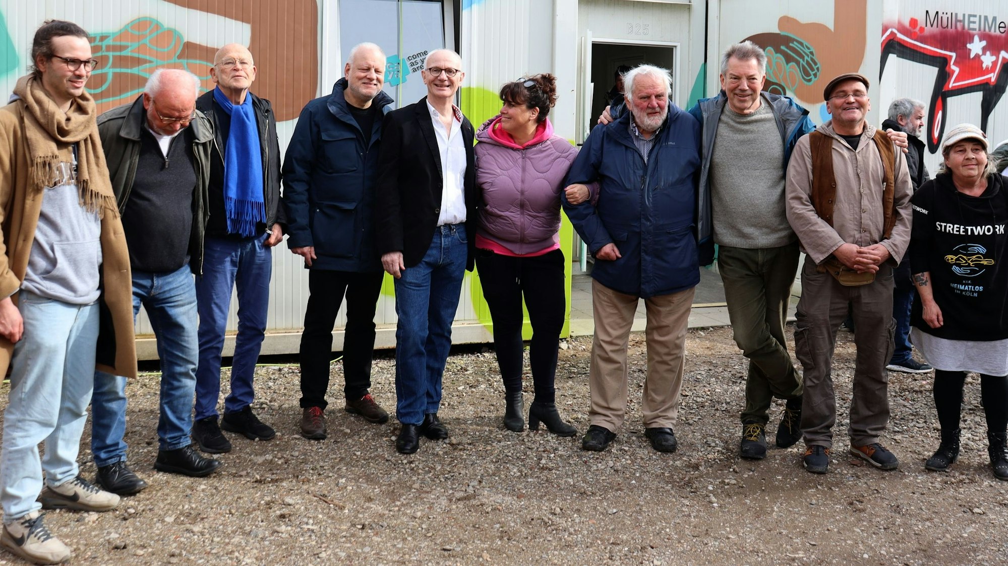 Die Menschen stehen vor bunten Containern.