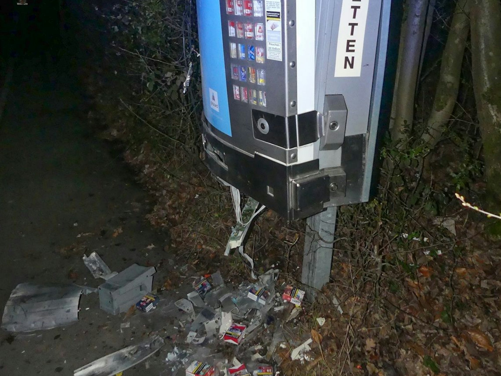Vor einem gesprengten Zigarettenautomaten liegen Dutzende zerstörte Zigarettenschachteln auf dem Boden.
