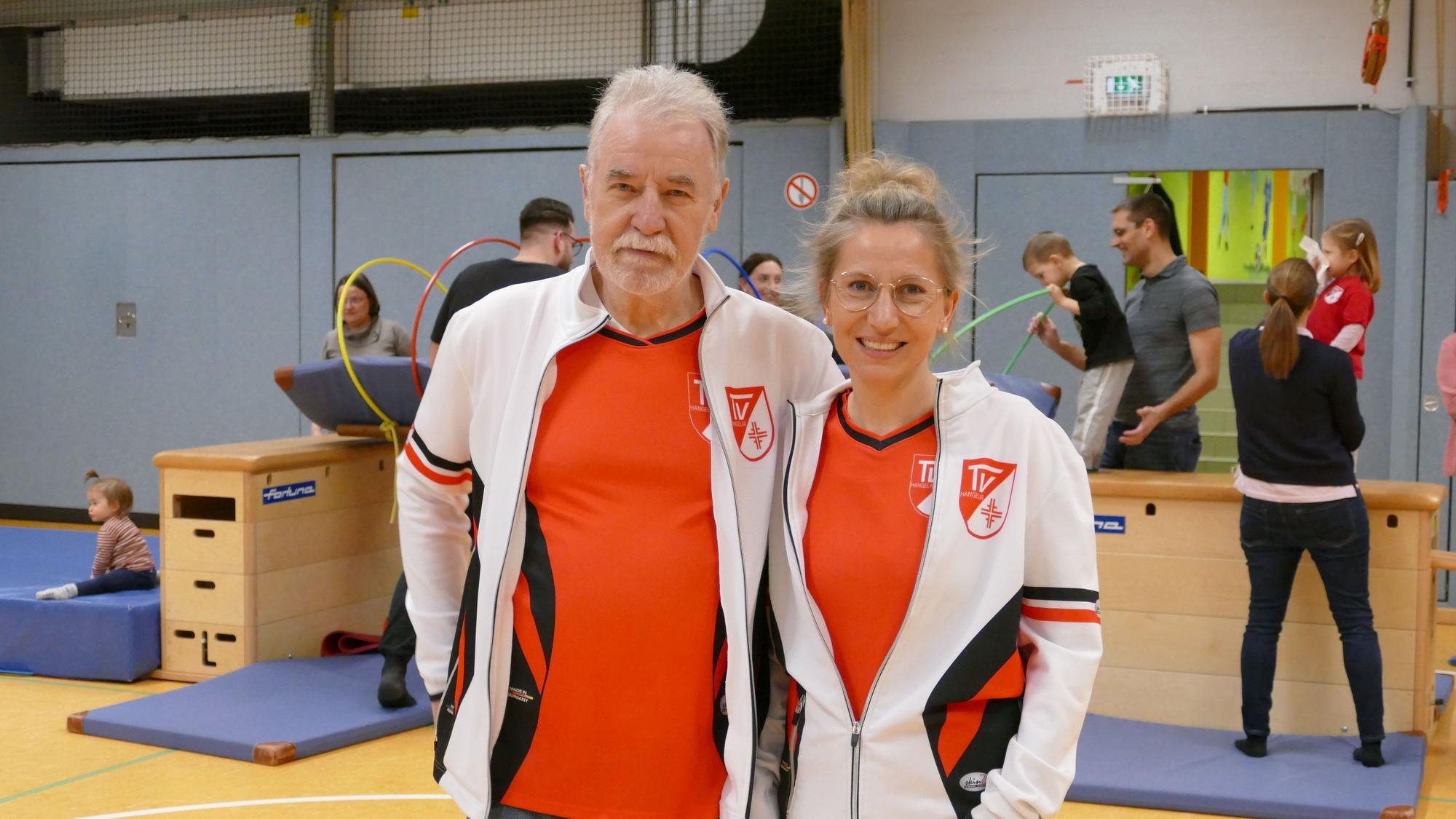 Eine Frau und ein Mann stehen in einer Sporthalle.