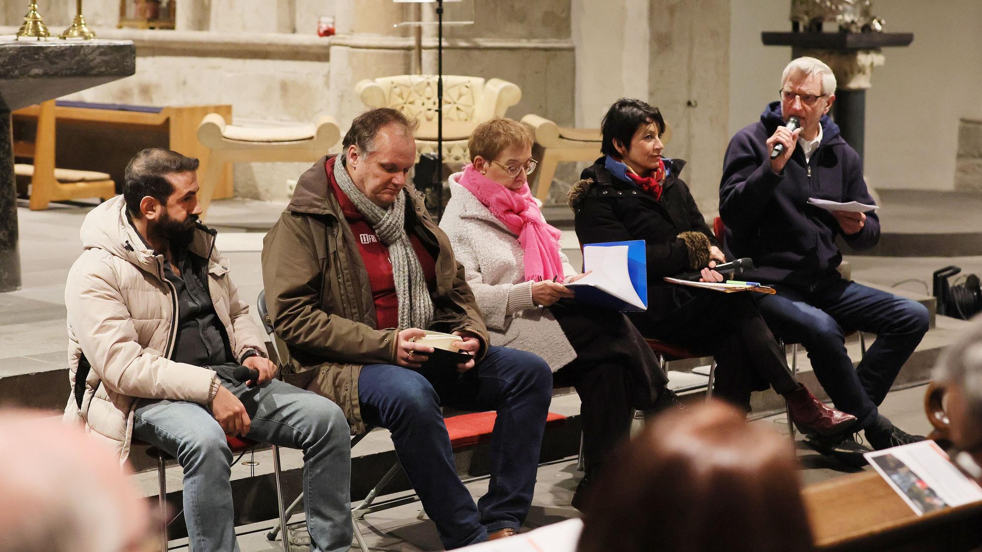 Fünf Menschen sitzen vor einem Altar auf Stühlen.