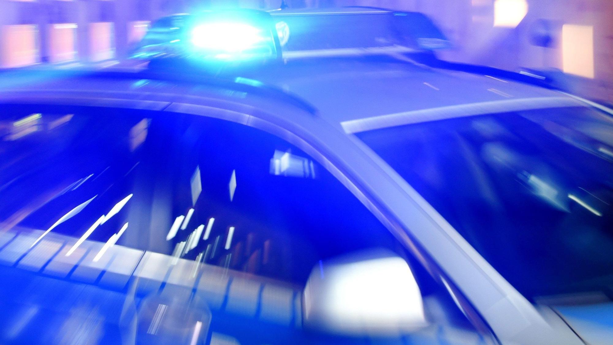 Ein Streifenwagen der Polizei steht mit eingeschaltetem Blaulicht auf der Straße.