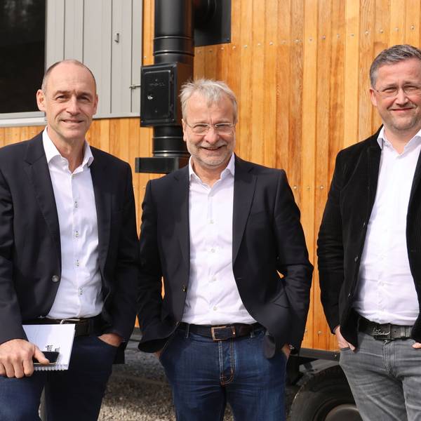 Gruppenfoto mit drei Herren vor einem Bauwagen.