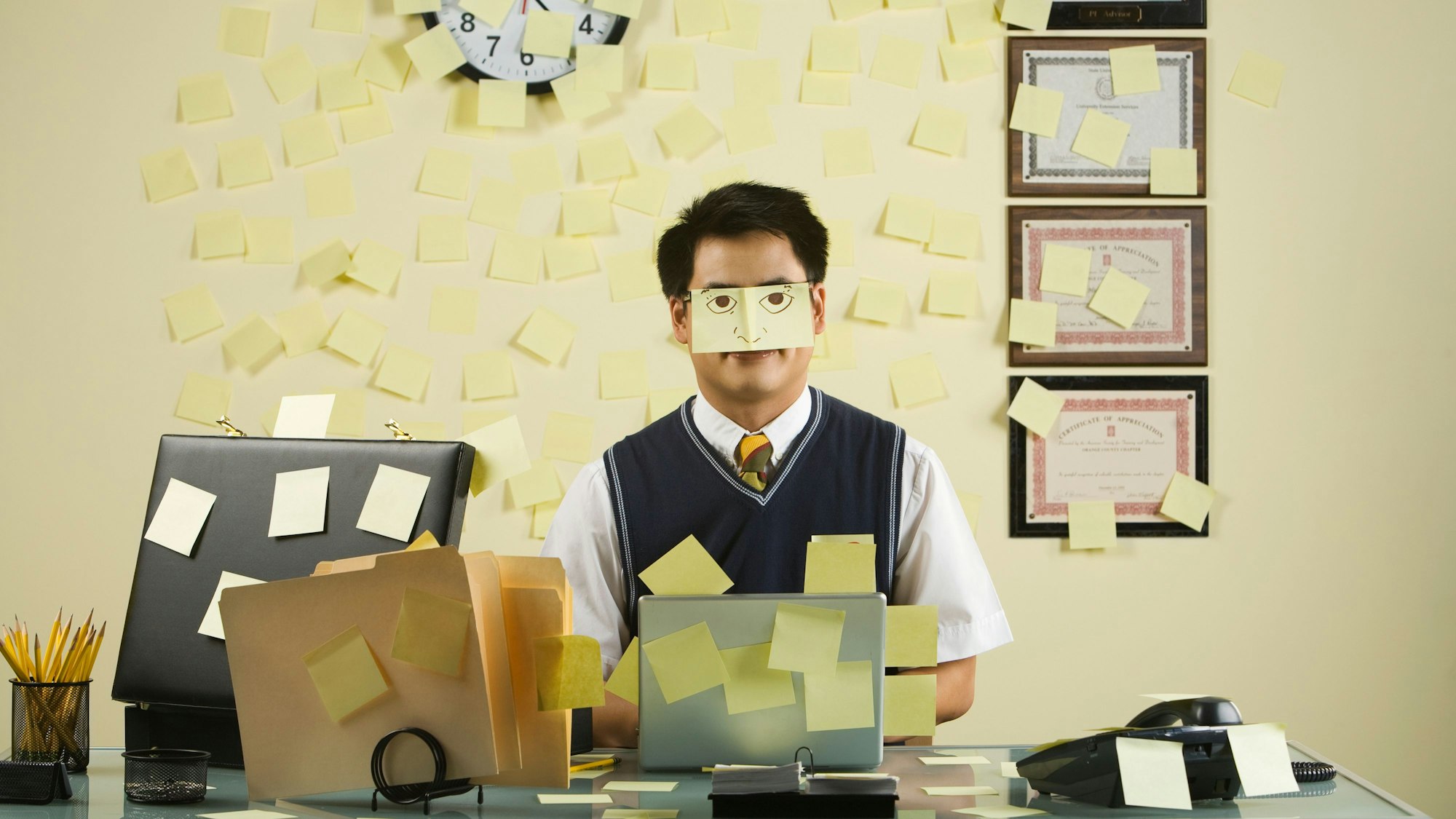 Ein Mann sitzt an einem Schreibtisch, dass mit Post-Its übersät ist.