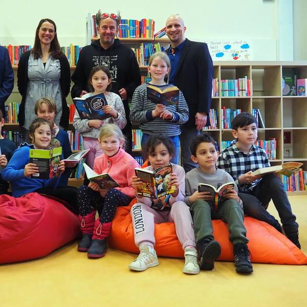 Grundschüler der Rosenzweiggrundschule in Zollstock sitzen auf bunten Sitzsäcken und halten Bücher in der Hand.