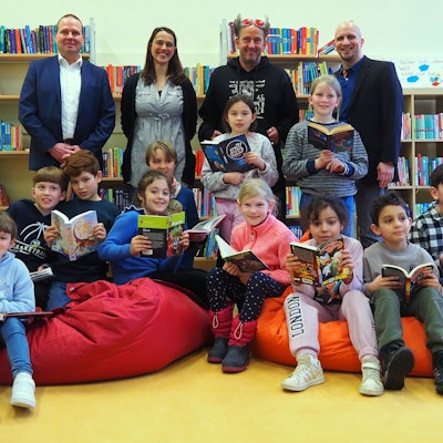 Grundschüler der Rosenzweiggrundschule in Zollstock sitzen auf bunten Sitzsäcken und halten Bücher in der Hand.