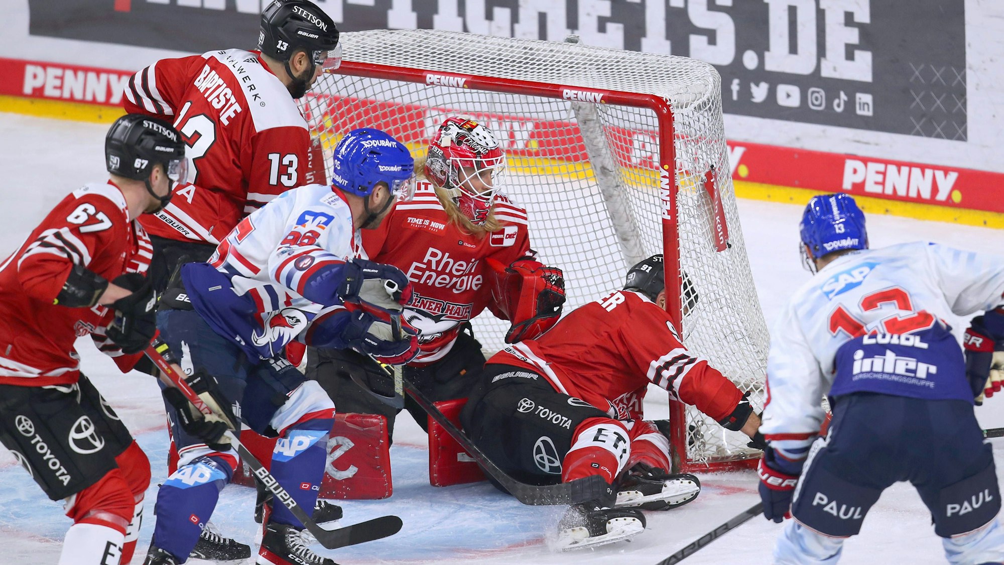 Hochbetrieb vor dem Kölner Tor: Haie-Kapitän Moritz Müller liegt sogar im Gehäuse von Goalie Mirko Pantkowski und fängt den Angriff von Mannheims Stefan Loibl (r.) ab