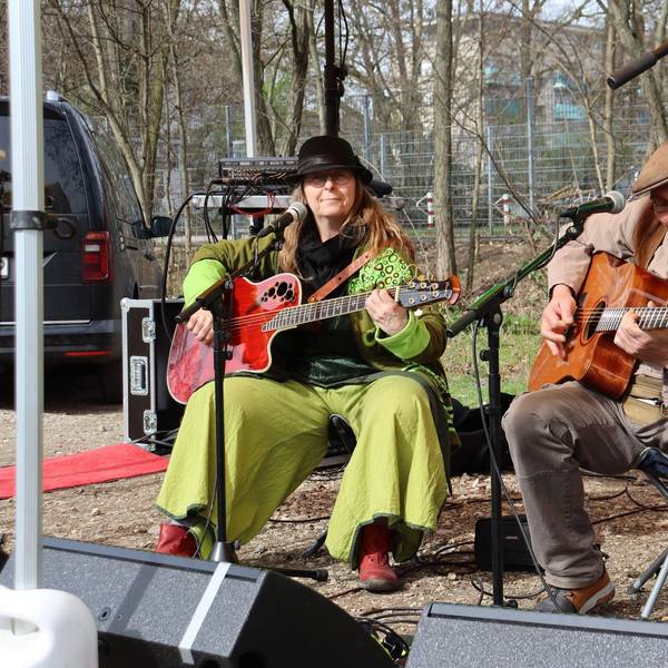 Zwei Personen spielen Gitarre auf einer provisorischen Bühne.