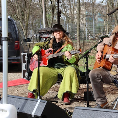 Zwei Personen spielen Gitarre auf einer provisorischen Bühne.