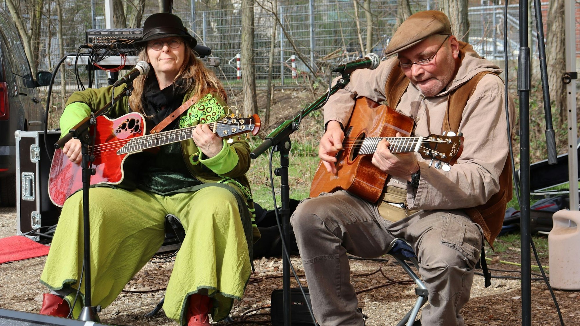 Zwei Personen spielen Gitarre auf einer provisorischen Bühne.
