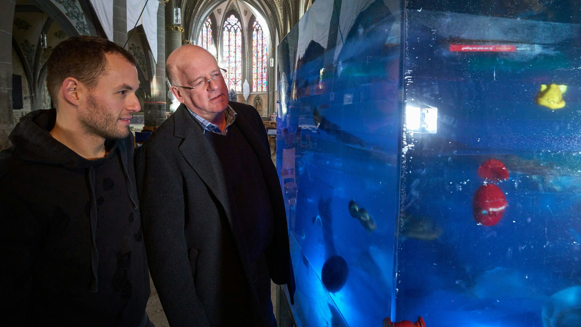 Die Initiatoren Marc Adeneuer (r) und Daniel Koller betrachten einen aus Kunstharz gegossenen Würfel namens «museum of modern ahrts». In dem Minimuseum wurden symbolträchtige Relikte der Ahr-Flut eingossen.
