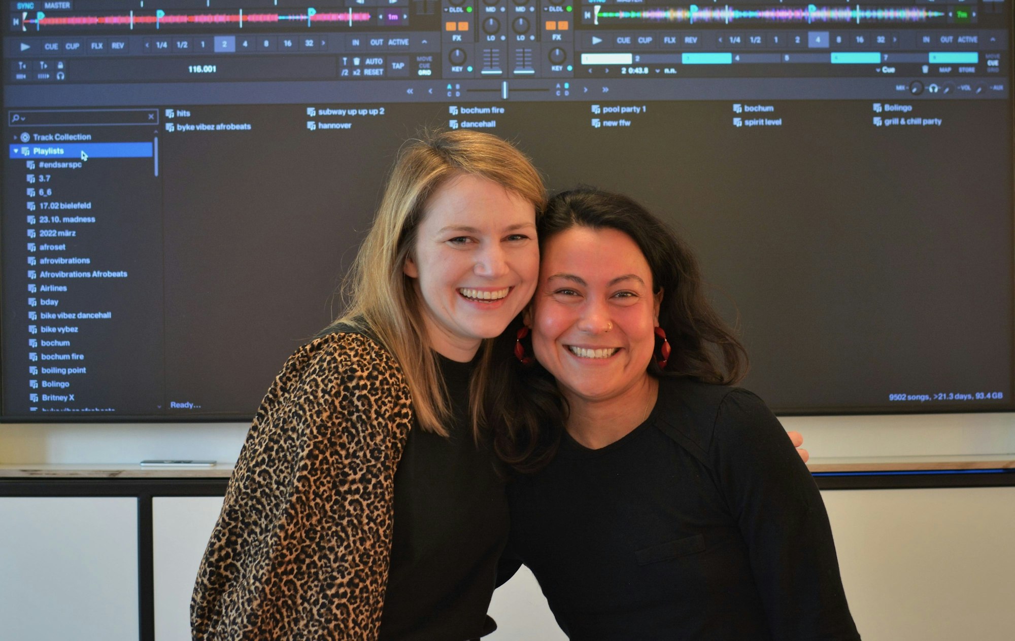 Zwei Frauen lachen in die Kamera, im Hintergrund sieht man auf einem Bildschirm Tonspuren.