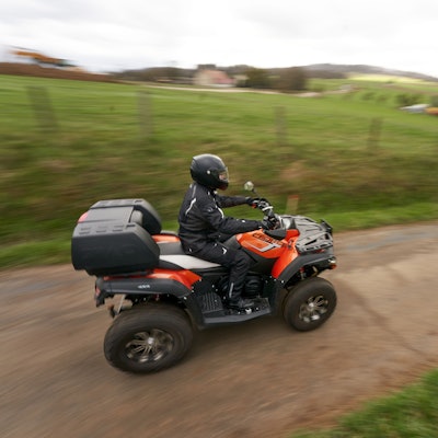 Ein Quadfahrer ist auf einer Landstrasse unterwegs.